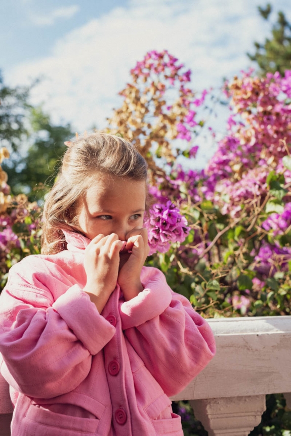 Veste Emma Marlot Paris devant des fleurs colorées